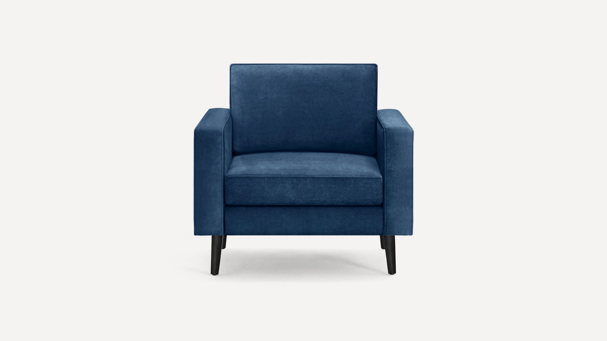 Blue velvet armchair with clean lines, square arms, cushioned back and seat, and dark tapered wooden legs.
