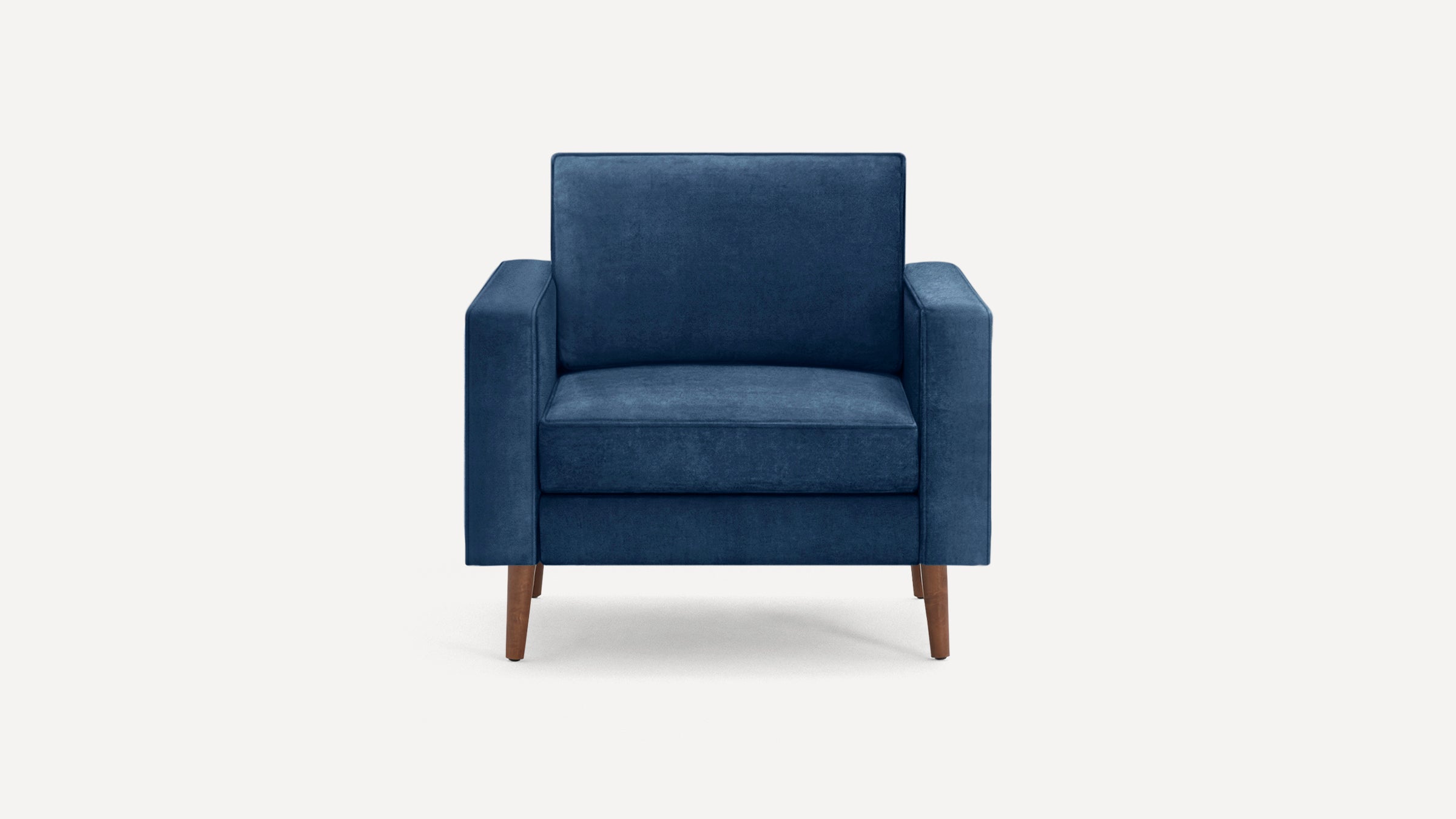 Front view of a modern navy blue velvet armchair with straight arms and wooden tapered legs on a white background.