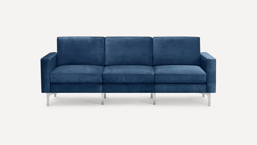 Modern three-seater sofa upholstered in deep blue velvet fabric with straight arms and sleek silver metal legs.