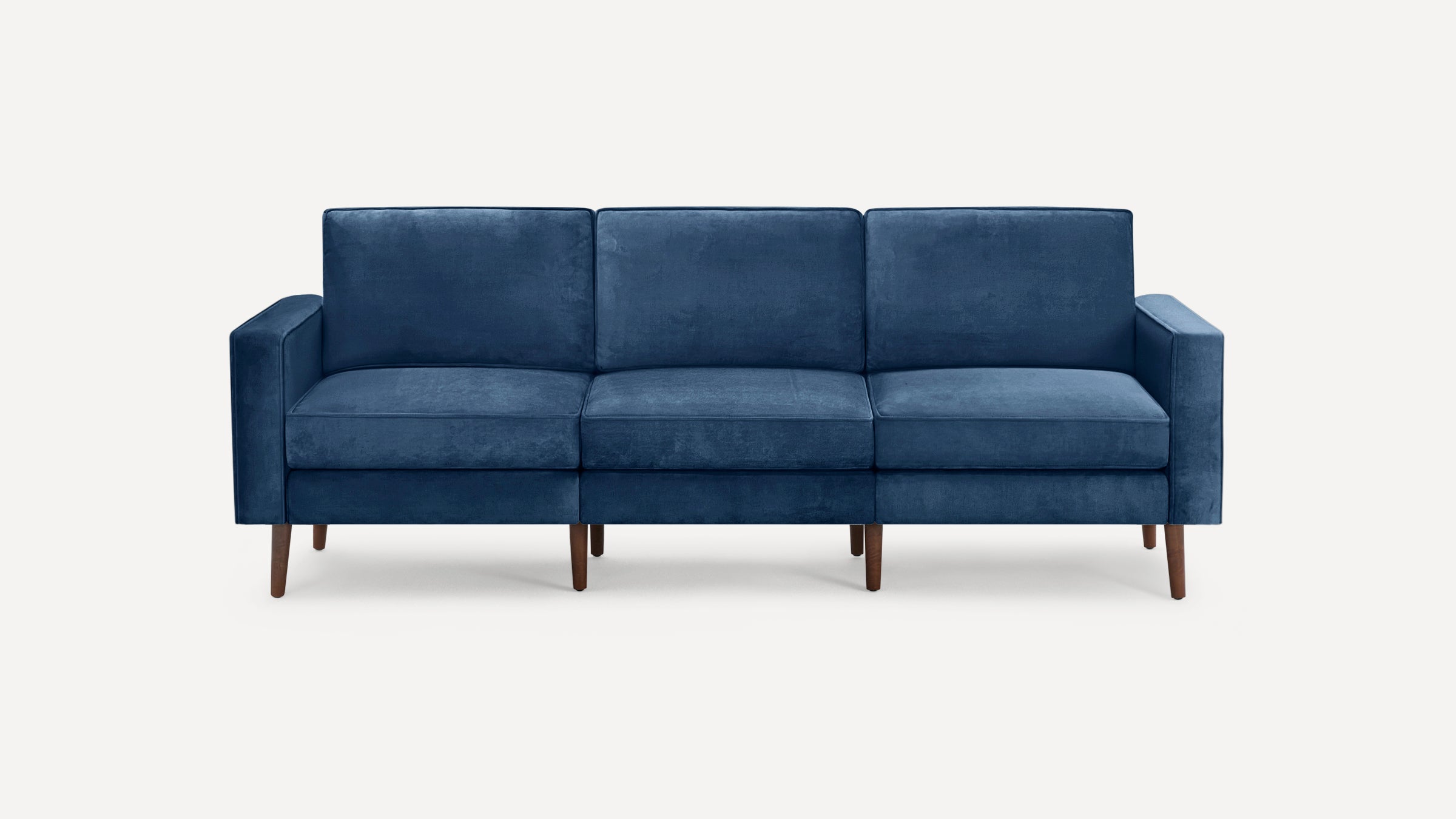 Modern navy blue three-seater sofa with plush cushions, straight arms, and wooden tapered legs on a white background.