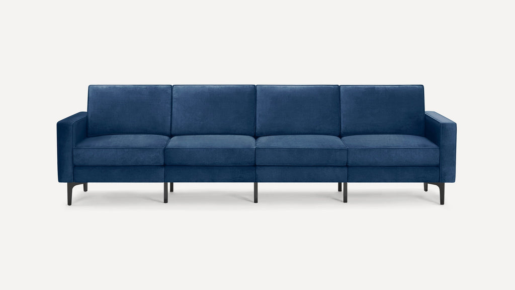 Modern four-seater sofa with deep blue velvet upholstery, straight arms, and slender black metal legs on a white background.