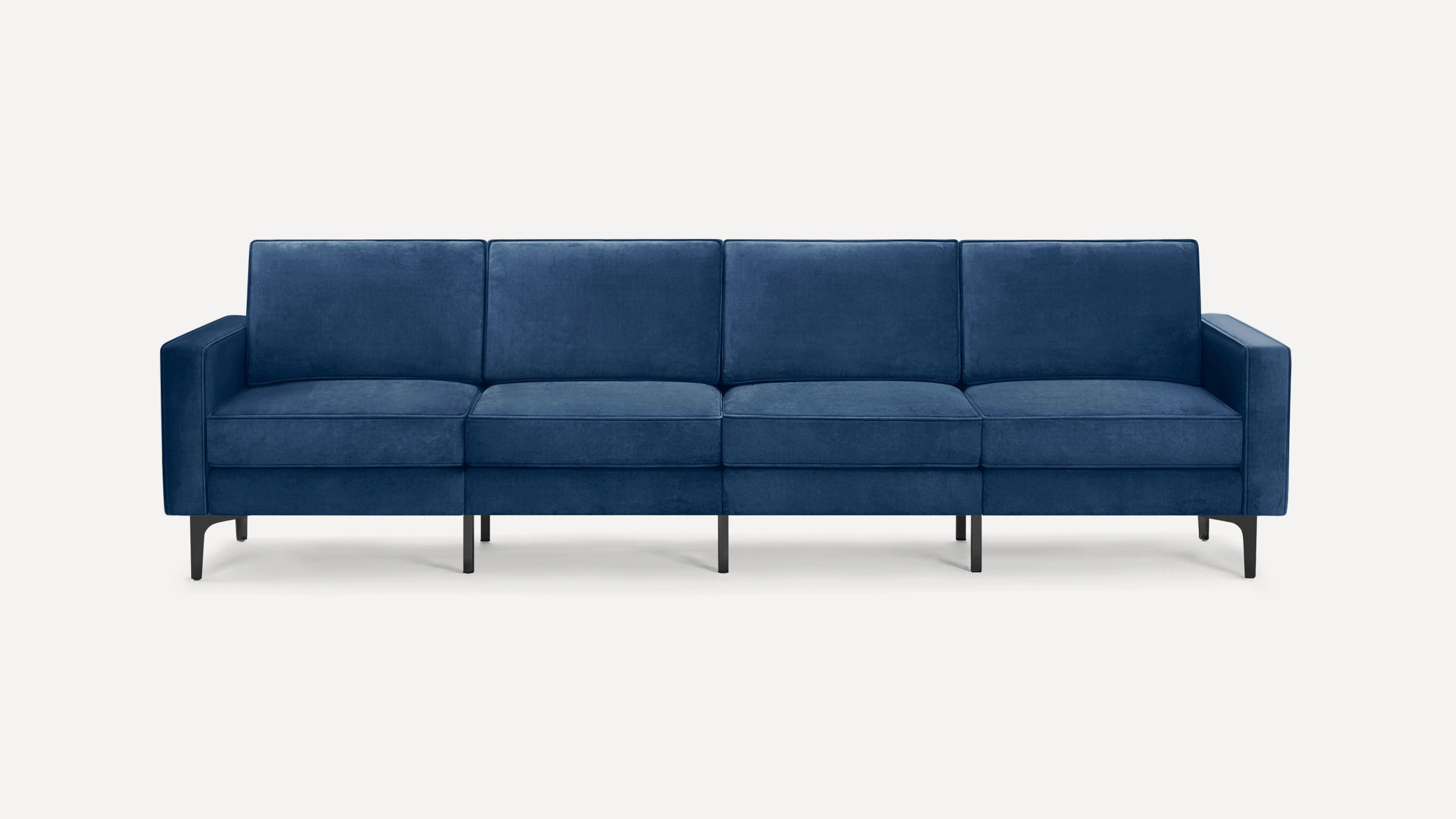 Modern four-seater sofa with deep blue velvet upholstery, straight arms, and slender black metal legs on a white background.