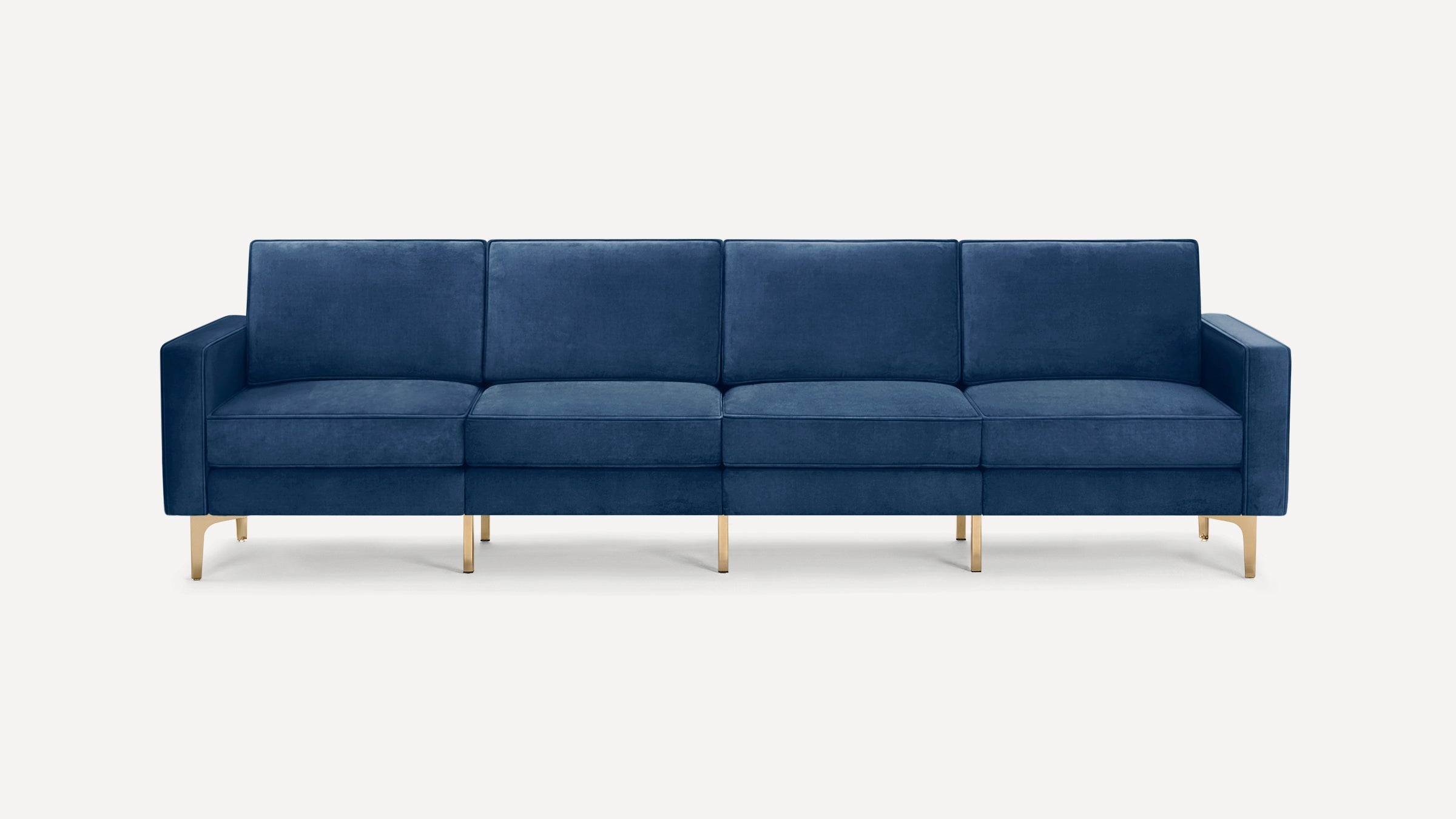 Modern four-seater sofa upholstered in deep blue velvet with clean lines and gold metal legs, against a white background.