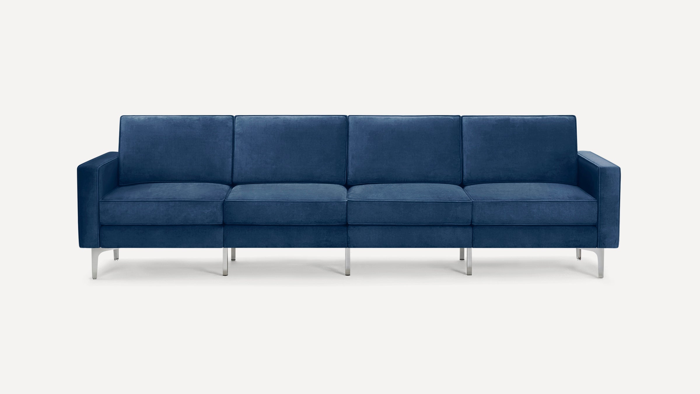 Modern four-seater sofa with deep blue velvet upholstery and sleek silver metal legs on a plain white background.
