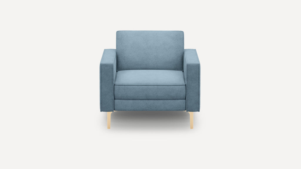 Front view of a modern blue upholstered armchair with thick cushions and light wooden legs on a white background.