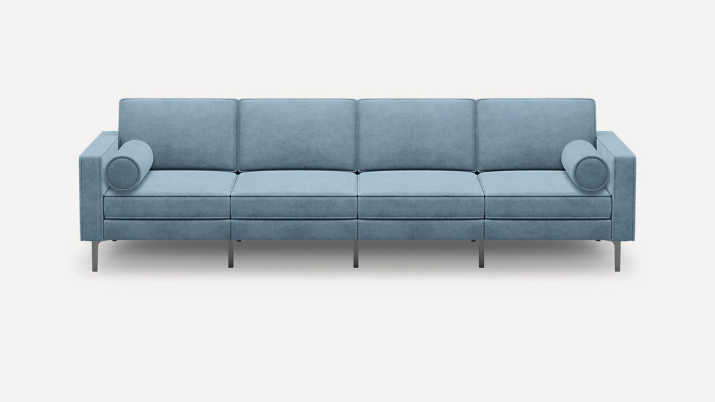 Modern light blue four-seater sofa with square arms, slim metal legs, and two cylindrical bolster pillows on each end.