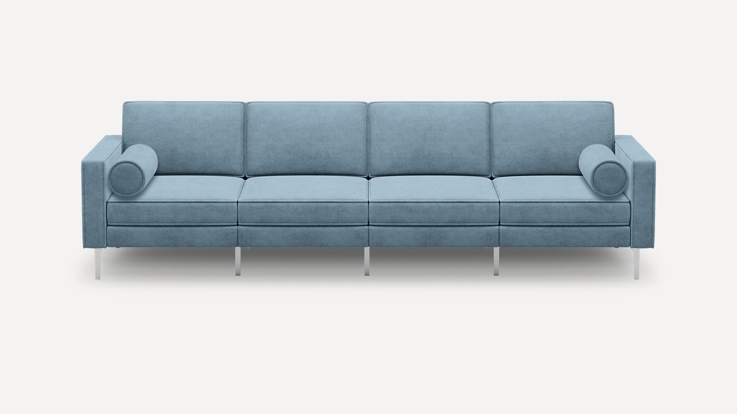 Modern light blue four-seater sofa with rectangular cushions, cylindrical bolster pillows, and slim metallic legs on a white background.