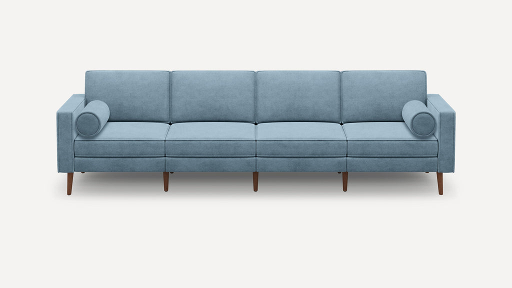 Light blue modern four-seater sofa with clean lines, square arms, cylindrical pillows, and wooden legs on a white background.