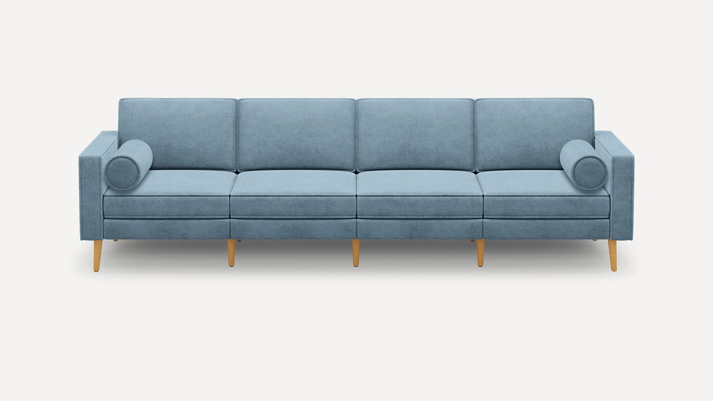 Modern light blue four-seater sofa with rectangular cushions, cylindrical arm pillows, and wooden tapered legs on a white background.