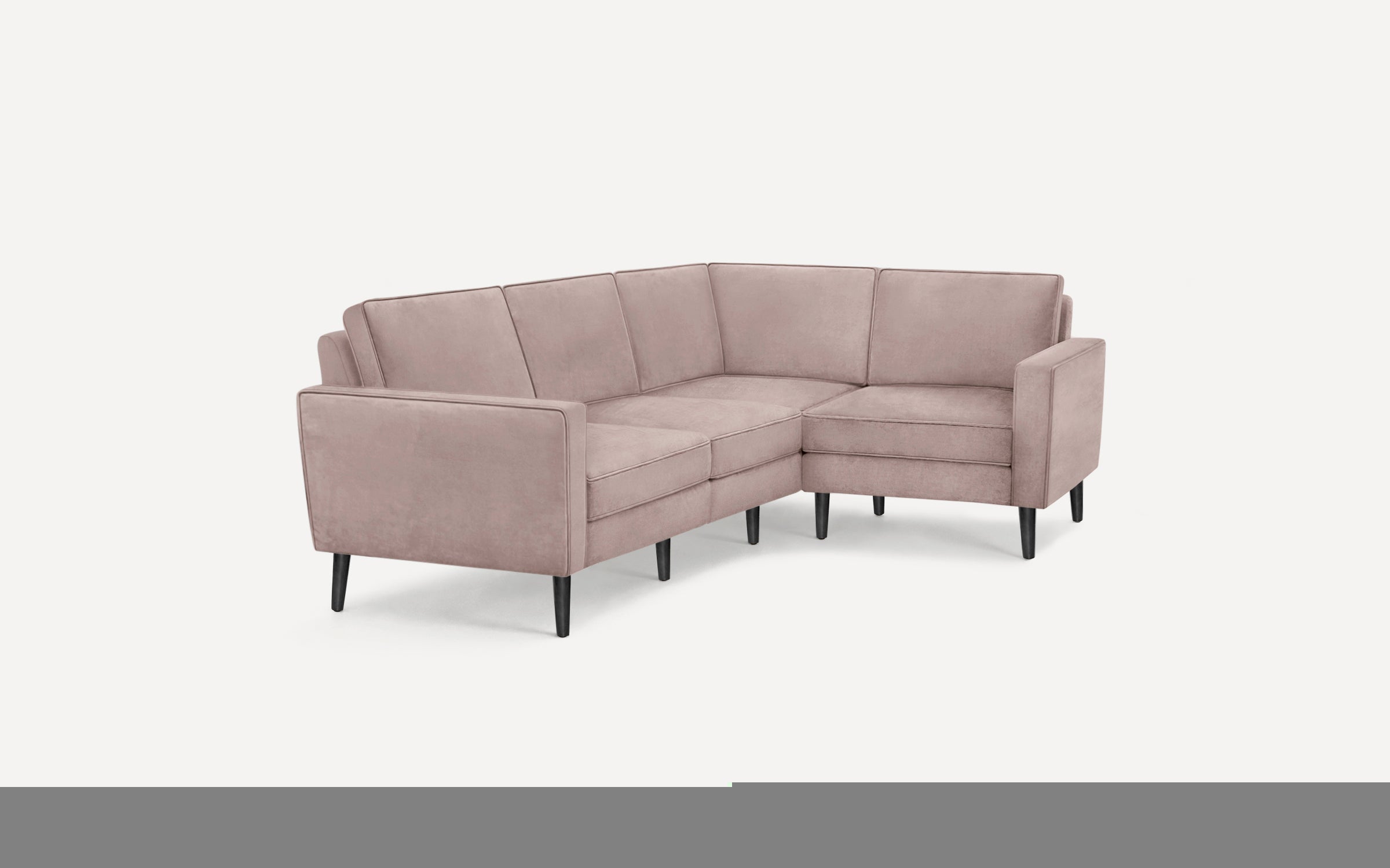 Modern L-shaped sectional sofa in soft pink upholstery with clean lines and slender black tapered legs.