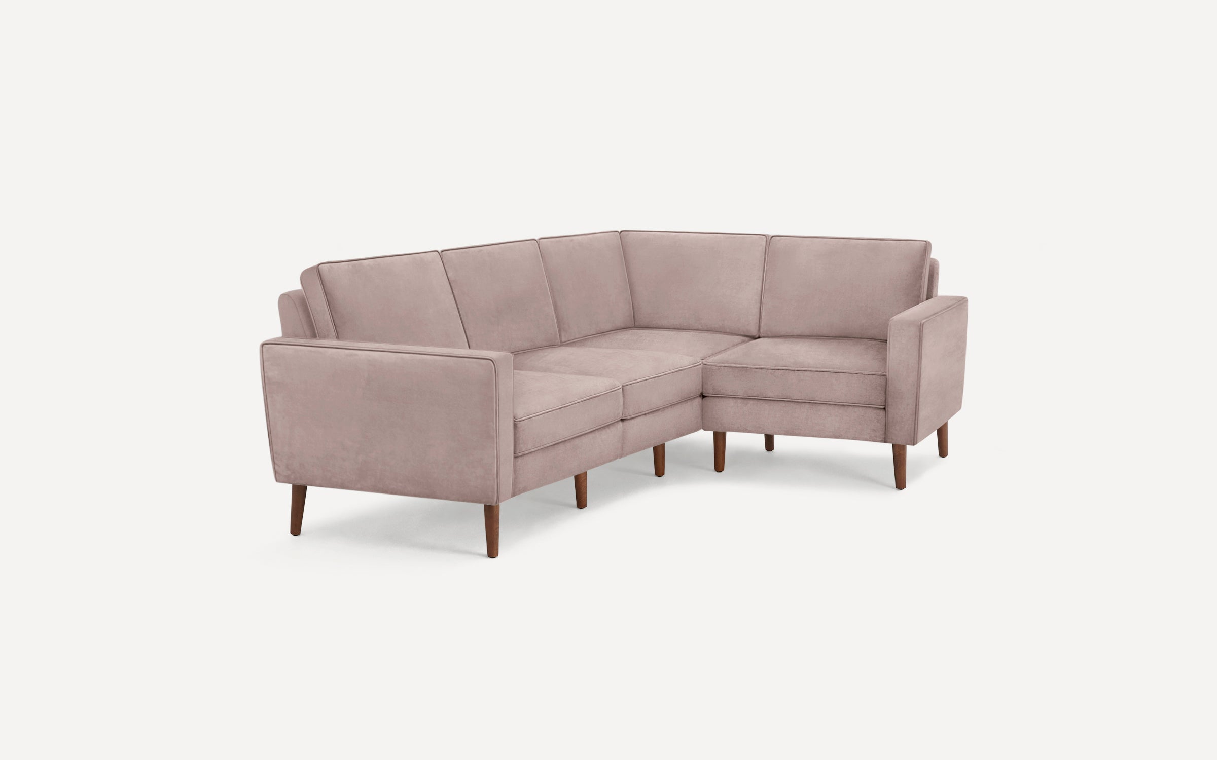 Modern L-shaped sectional sofa with soft pink upholstery and wooden tapered legs on a plain white background.