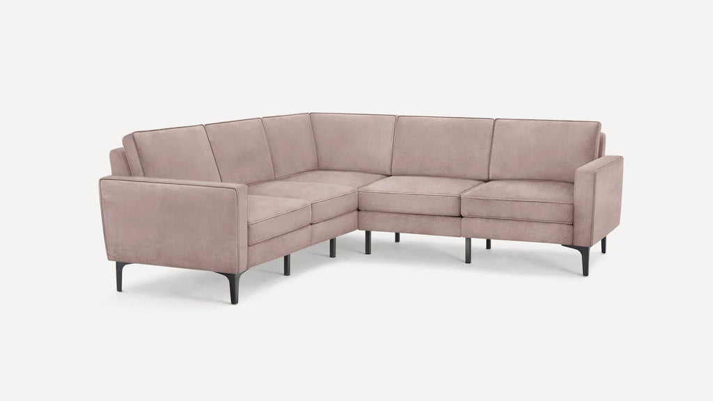 Modern L-shaped sectional sofa with soft dusty pink upholstery and thin black metal legs, set against a white background.