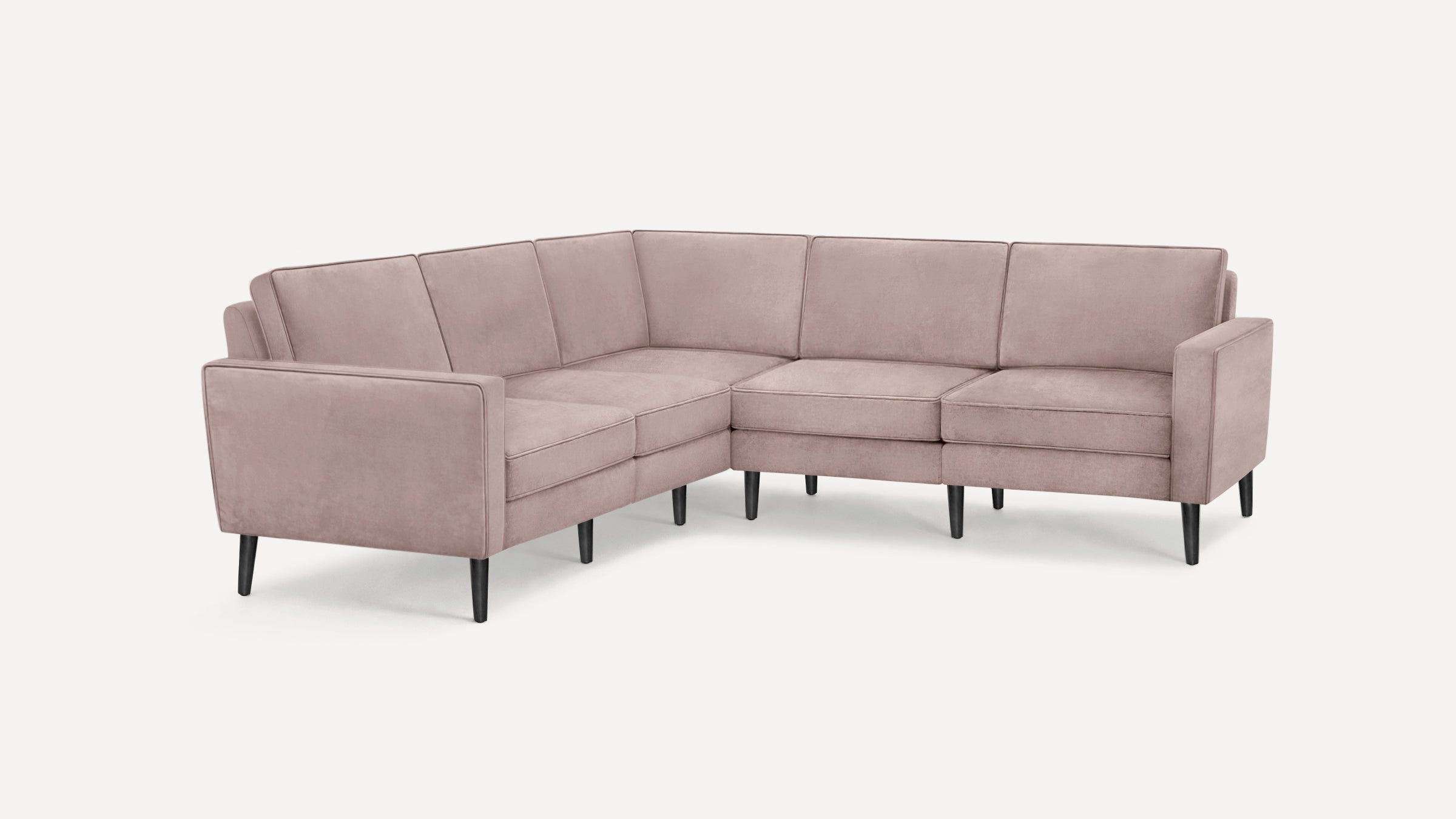 Light pink velvet L-shaped sectional sofa with black tapered wooden legs on white background.