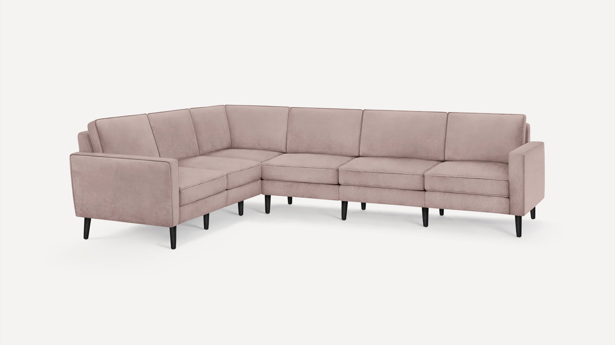 Modern L-shaped sectional sofa upholstered in soft dusty pink fabric with black tapered legs, offering spacious seating.