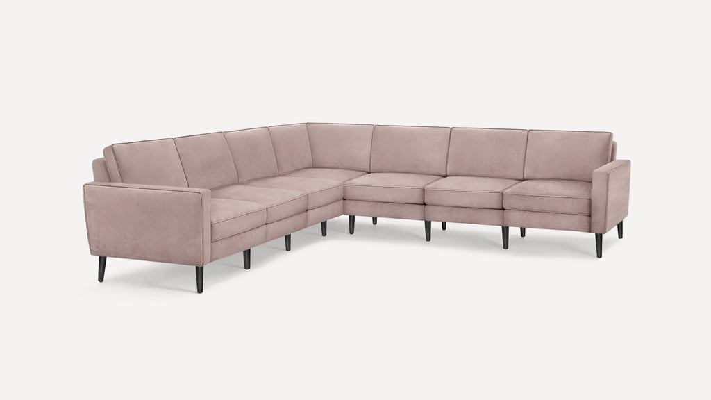 L-shaped sectional sofa with light mauve upholstery, tufted cushions, sleek black tapered legs, and modern clean-lined design.