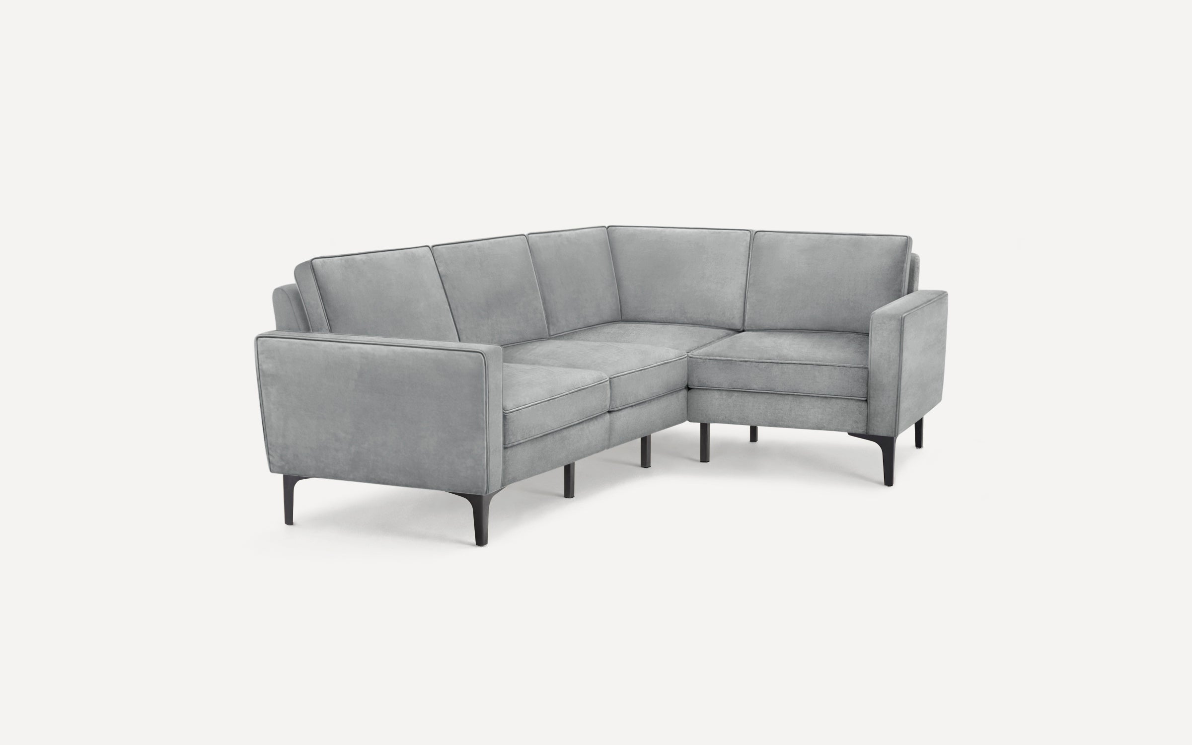 Light gray velvet L-shaped sectional sofa with slim black legs and boxy armrests against white background.