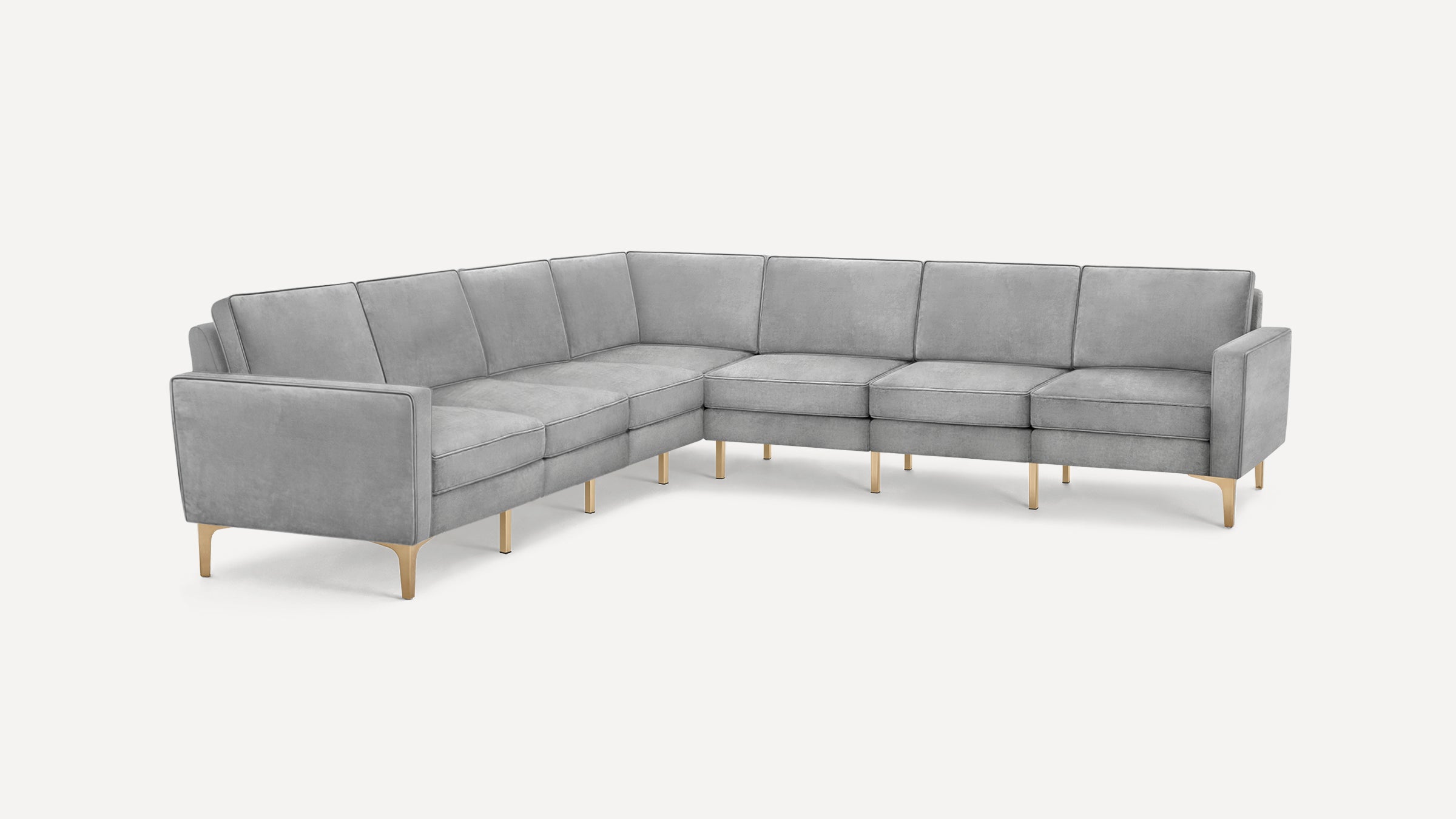 Modern L-shaped sectional sofa in light gray velvet with slim gold metal legs and plush cushions on a white background.