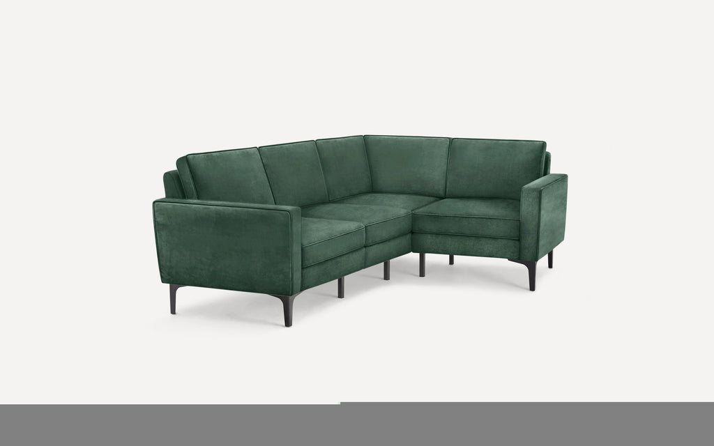 Green velvet L-shaped sectional sofa with sleek black legs and modern design, set against a plain background.