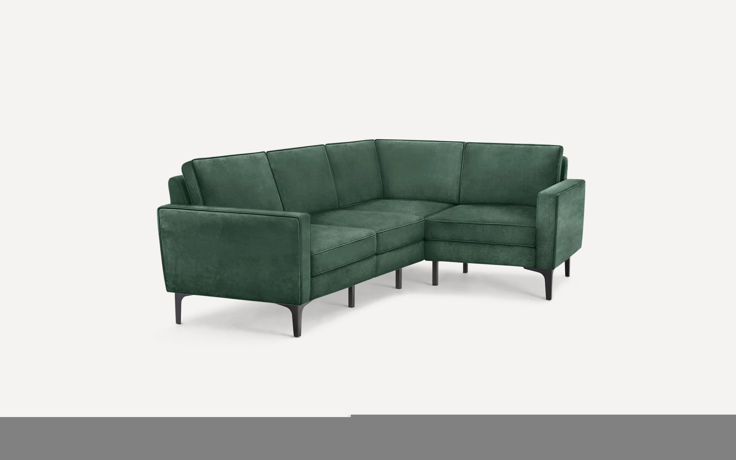 Green velvet L-shaped sectional sofa with sleek black legs and modern design, set against a plain background.