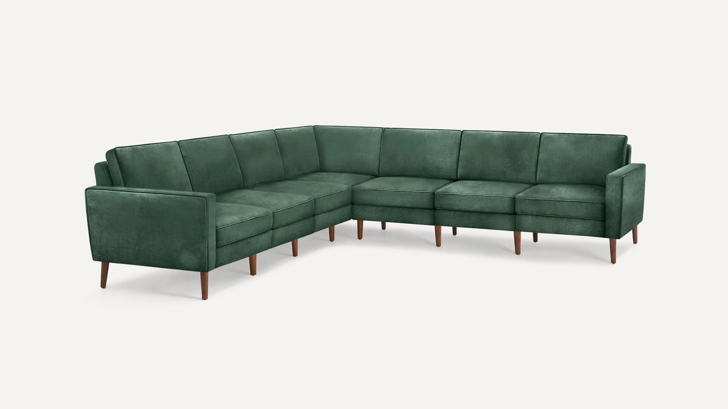 L-shaped sectional sofa in dark green velvet upholstery with wooden tapered legs and clean, modern design.