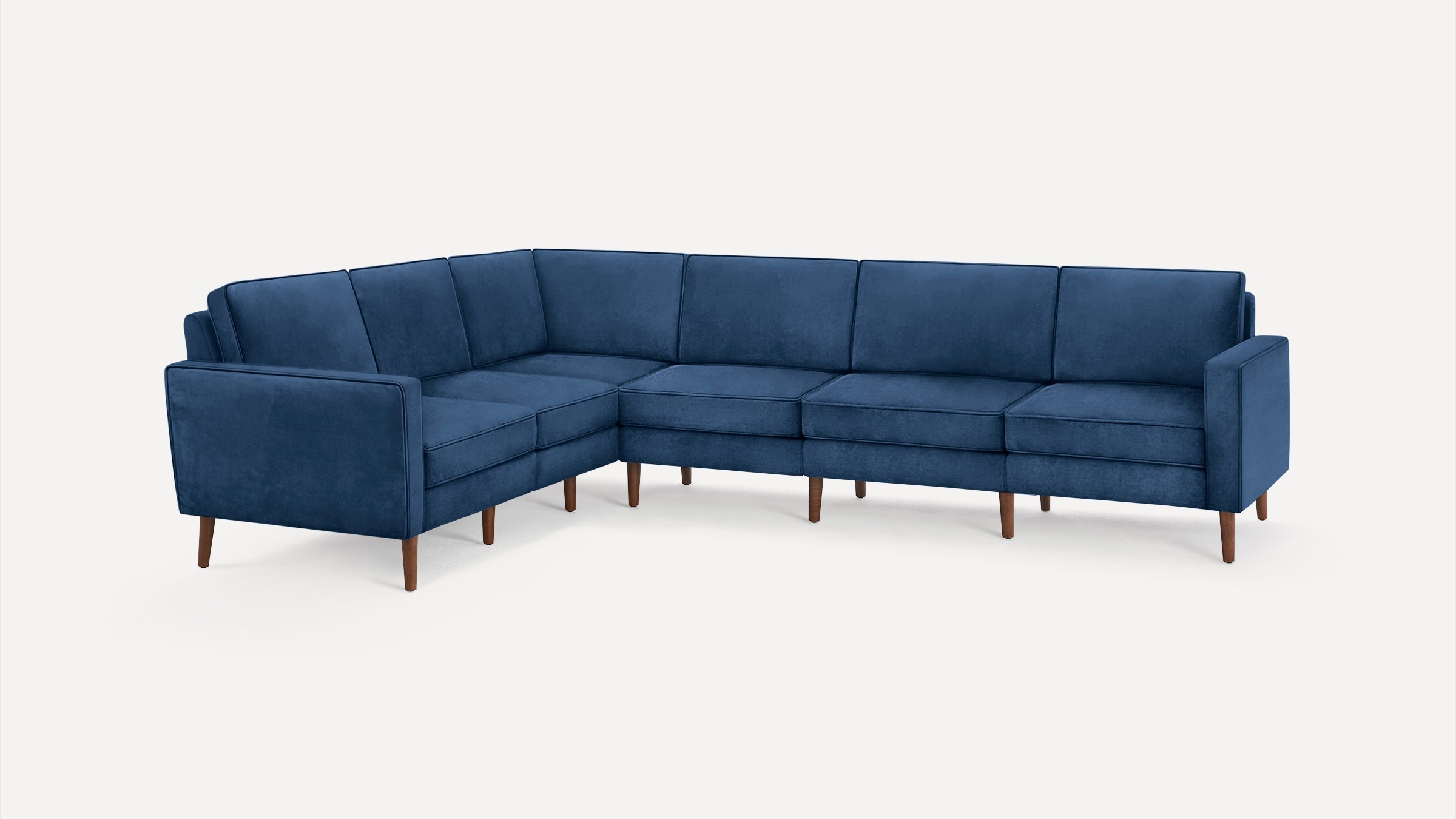 L-shaped sectional sofa in deep blue velvet upholstery with clean lines and wooden tapered legs, suitable for modern living spaces.