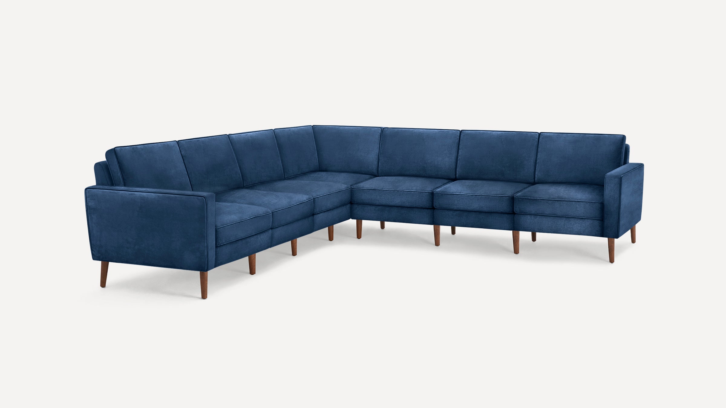 L-shaped sectional sofa upholstered in deep blue fabric with wooden legs and clean, modern lines.
