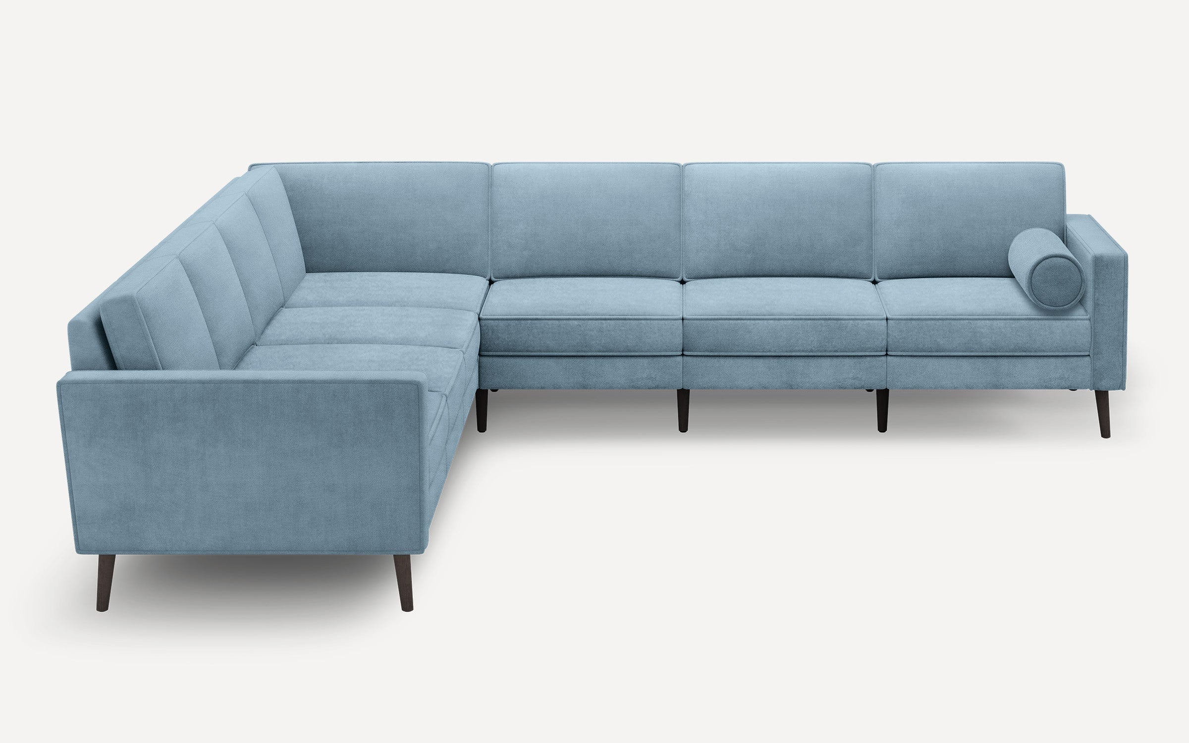 Modern light blue L-shaped sectional sofa with clean lines, tufted cushions, cylindrical pillow, and dark wooden legs.