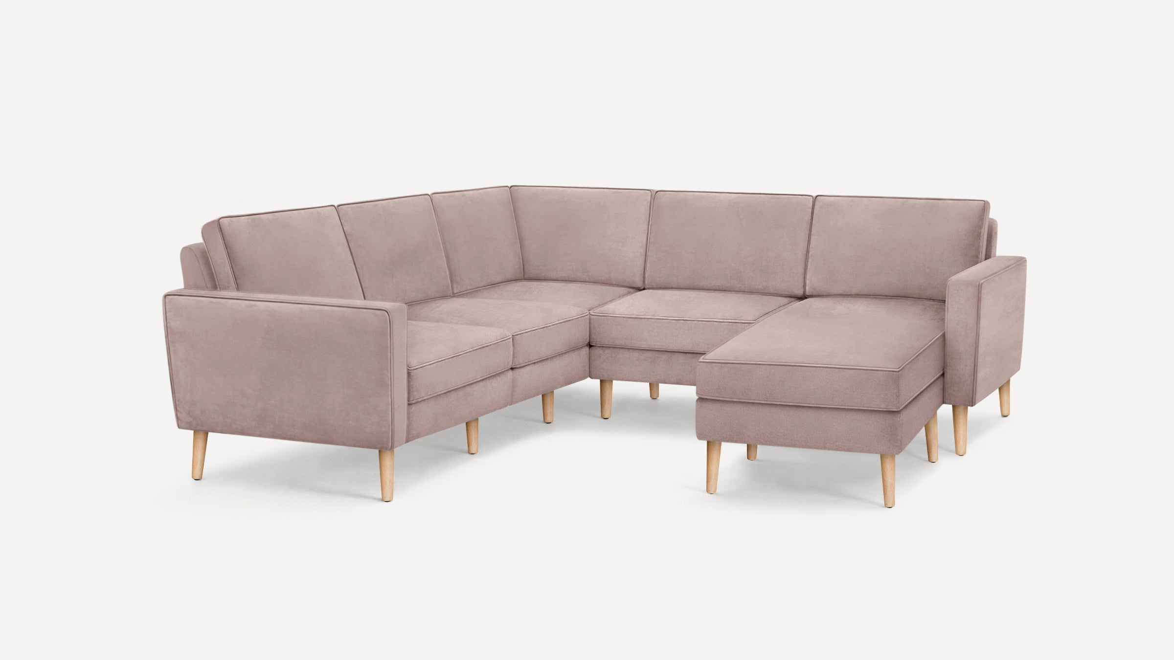 Light mauve L-shaped sectional sofa with straight armrests and wooden legs on white background.