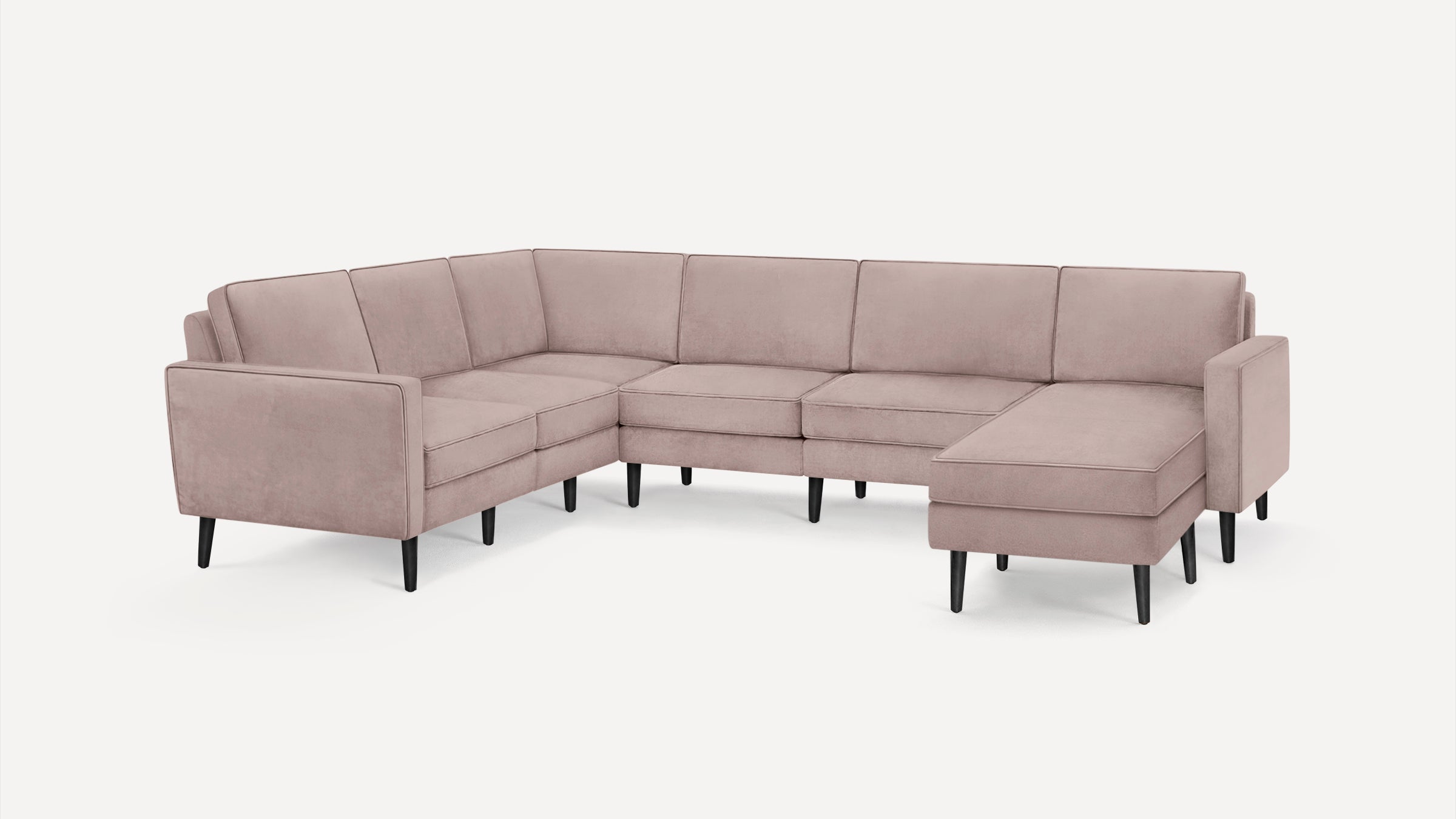 Modern L-shaped sectional sofa in soft pink fabric with clean lines and black tapered wooden legs.