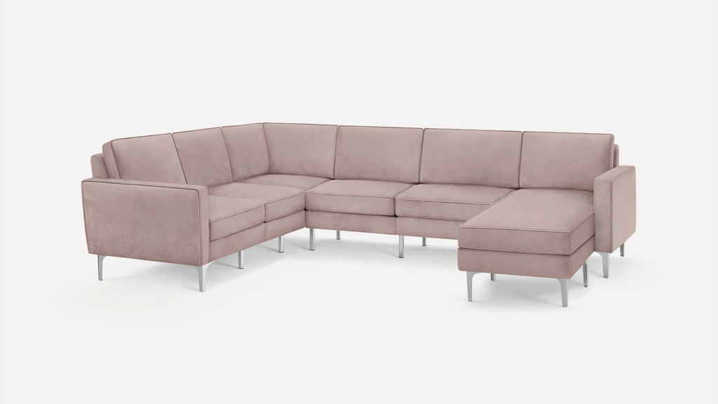 Modern L-shaped sectional sofa in soft blush pink fabric with metal legs, featuring clean lines and padded cushions.