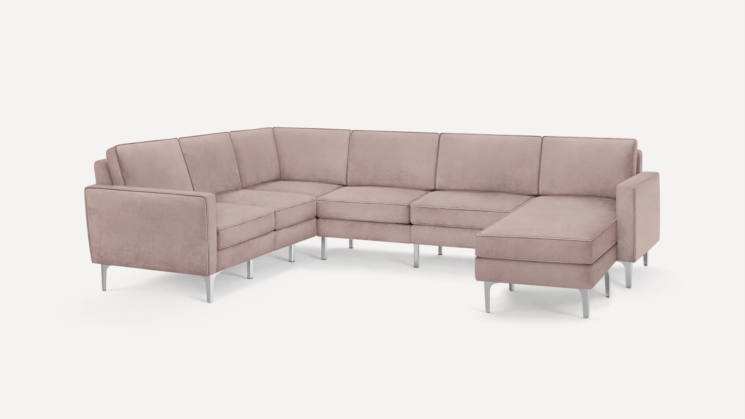 Modern L-shaped sectional sofa in soft blush pink fabric with metal legs, featuring clean lines and padded cushions.