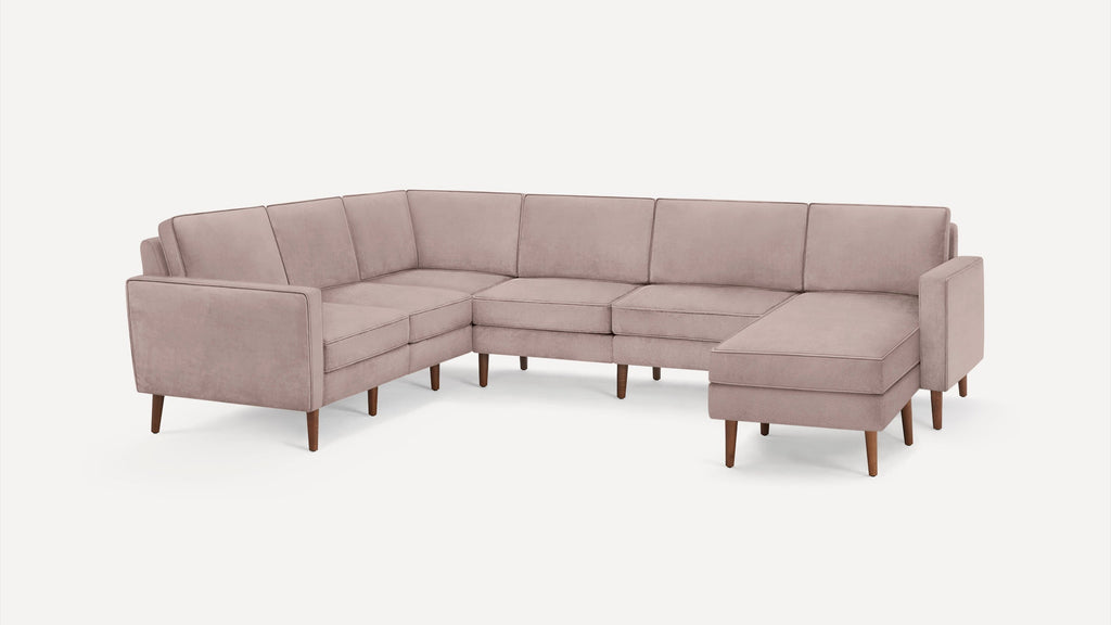 Modern L-shaped sectional sofa in muted pink fabric with clean lines and wooden tapered legs on white background.