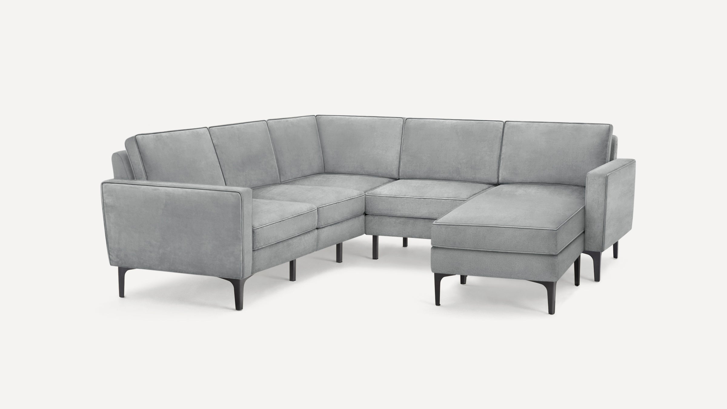 Modern L-shaped sectional sofa in soft gray fabric with slim black legs and cushioned backrests and seats.