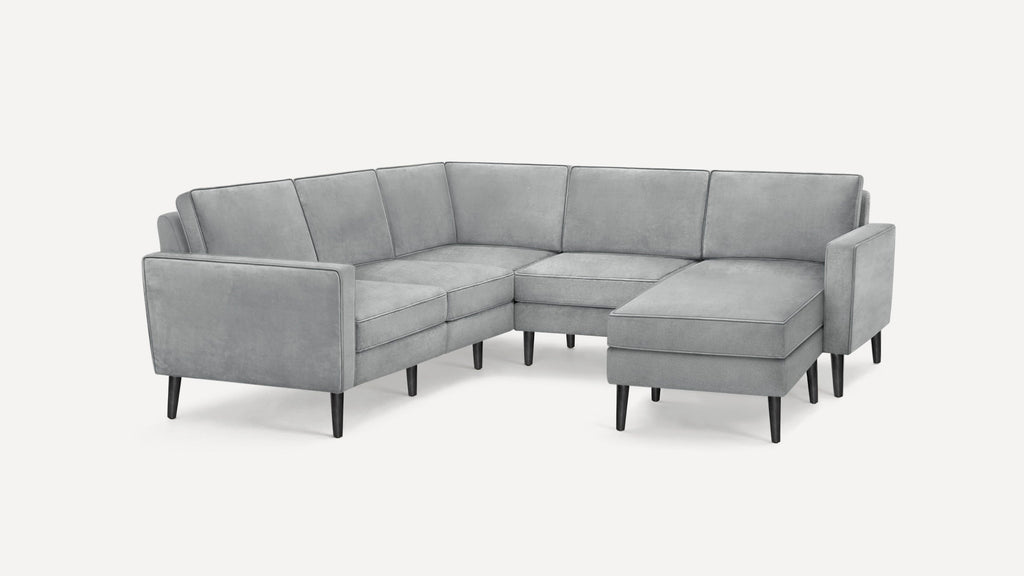Modern light gray velvet sectional sofa with thin black legs and clean, angular design.