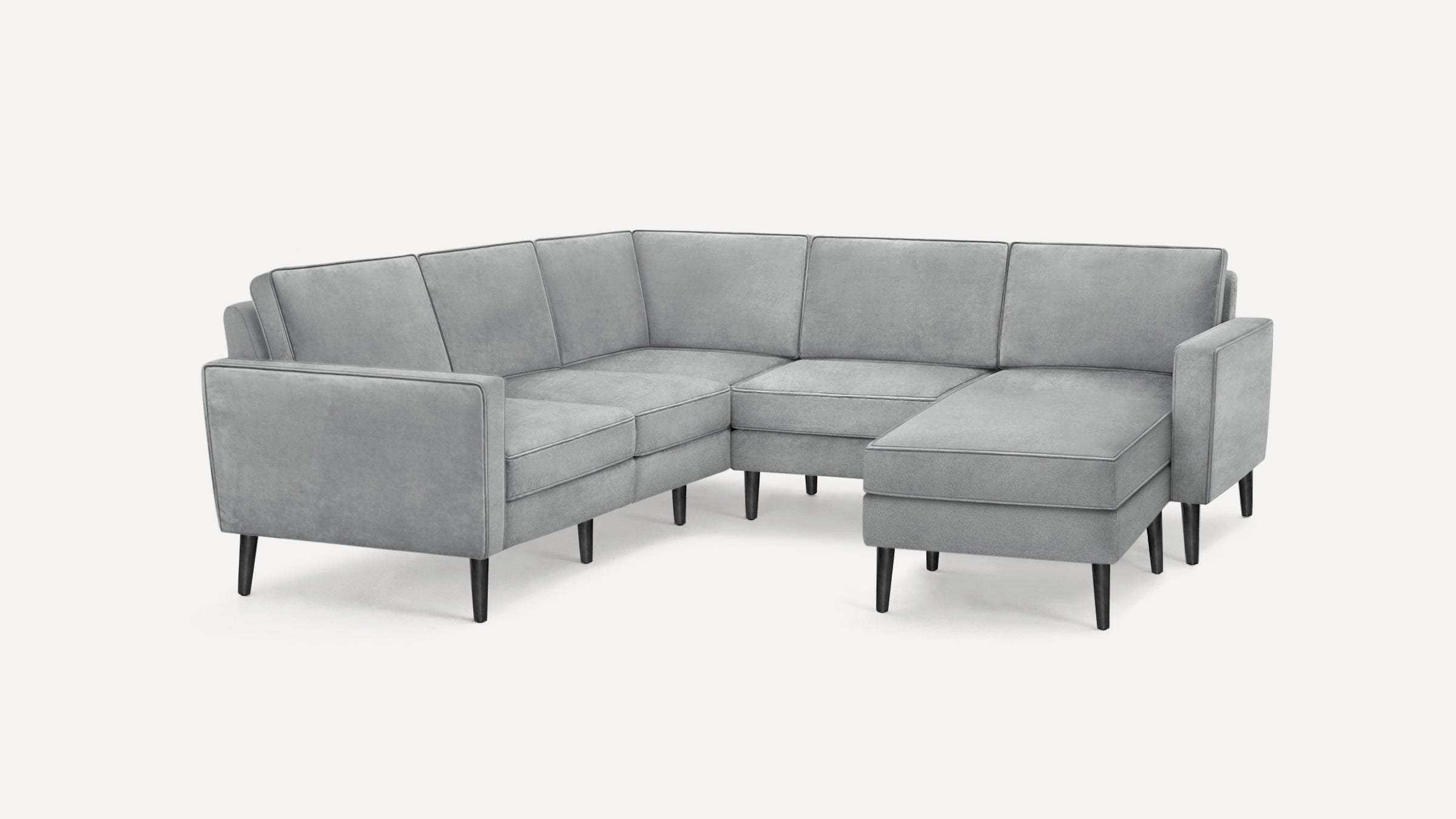 Modern light gray velvet sectional sofa with thin black legs and clean, angular design.
