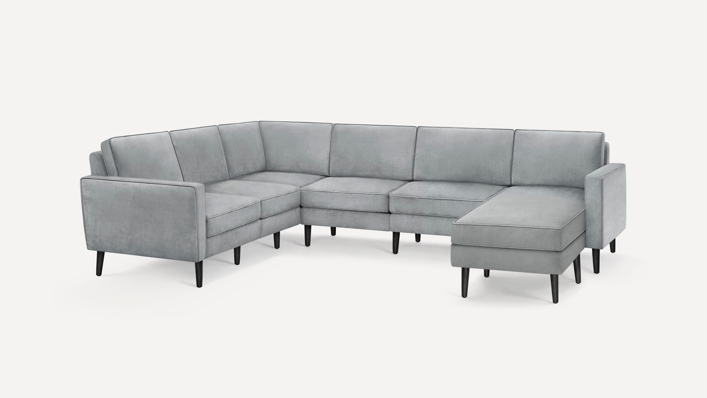 Modern light gray velvet sectional sofa with black tapered legs, L-shaped design including a chaise lounge on one end.