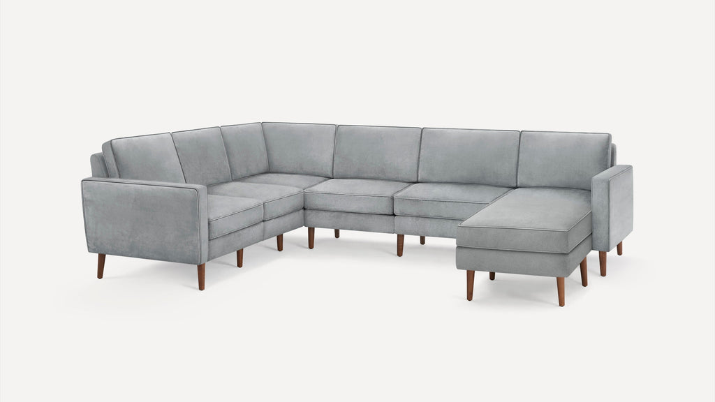 Light gray modern sectional sofa with velvet upholstery, clean lines, angled wooden legs, and an L-shaped design with chaise lounge.