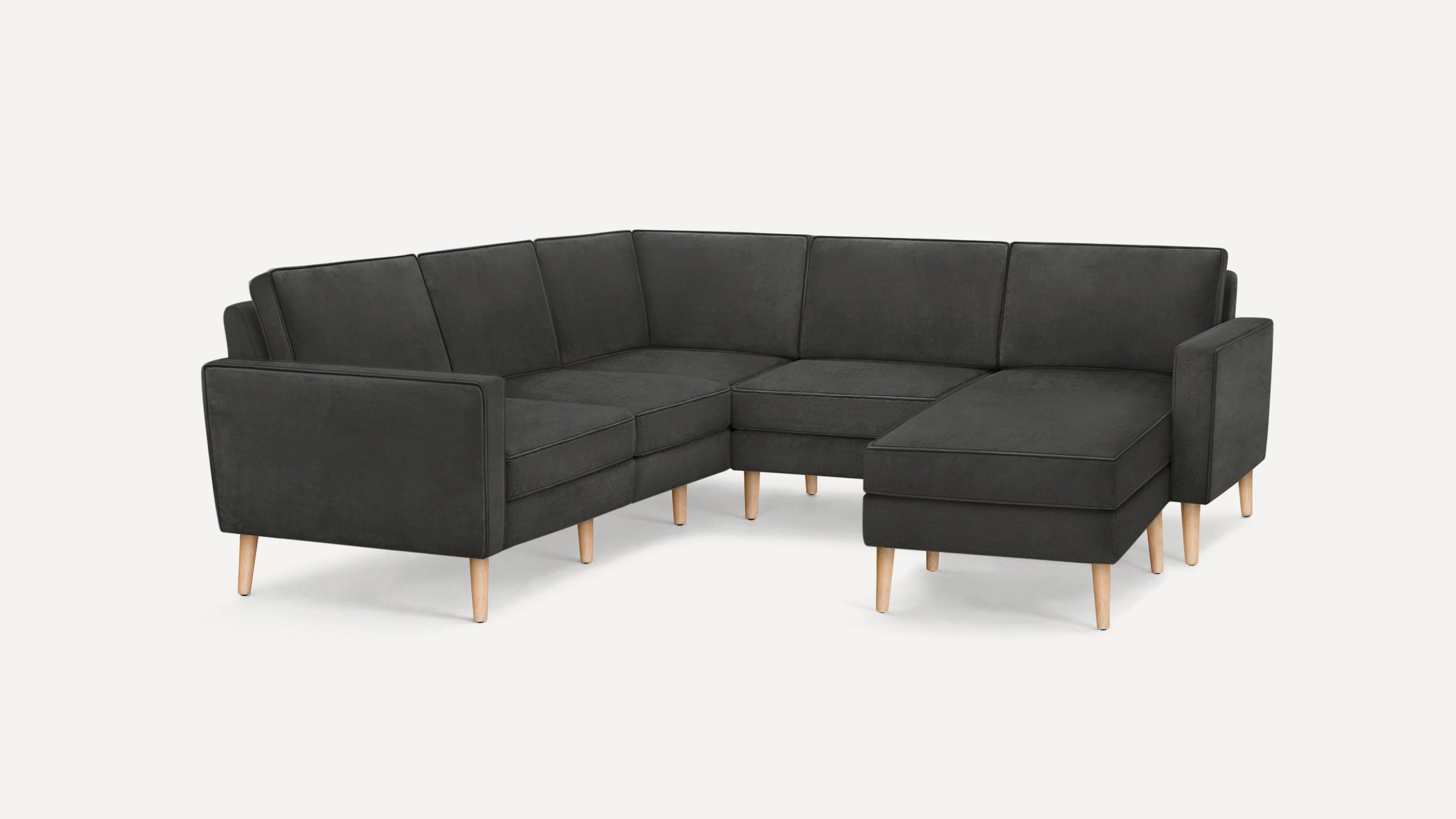 Dark gray L-shaped sectional sofa with wooden tapered legs and clean, modern design in a studio setting.
