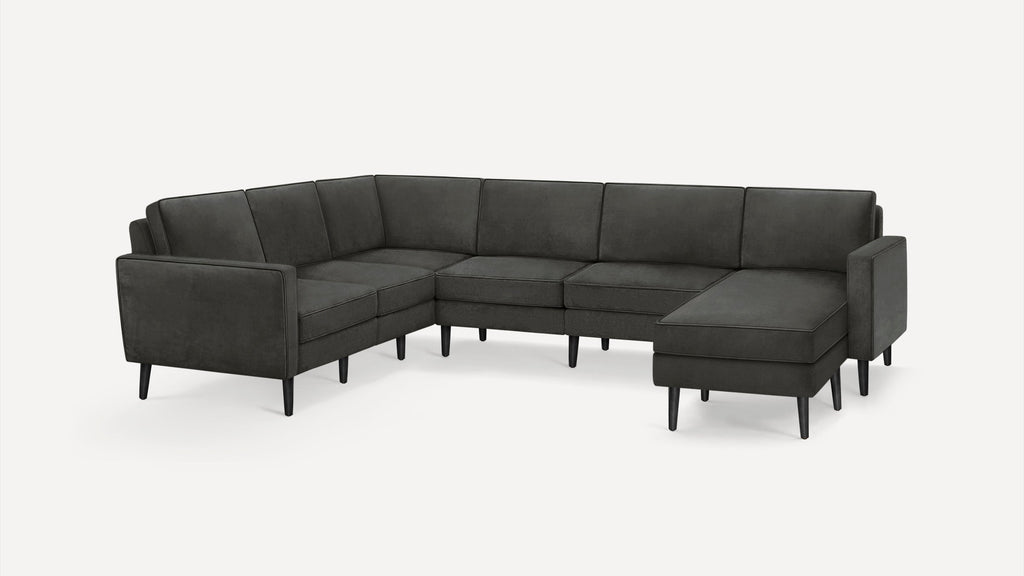 Modern L-shaped sectional sofa with dark gray upholstery and slender black wooden legs on a white background.