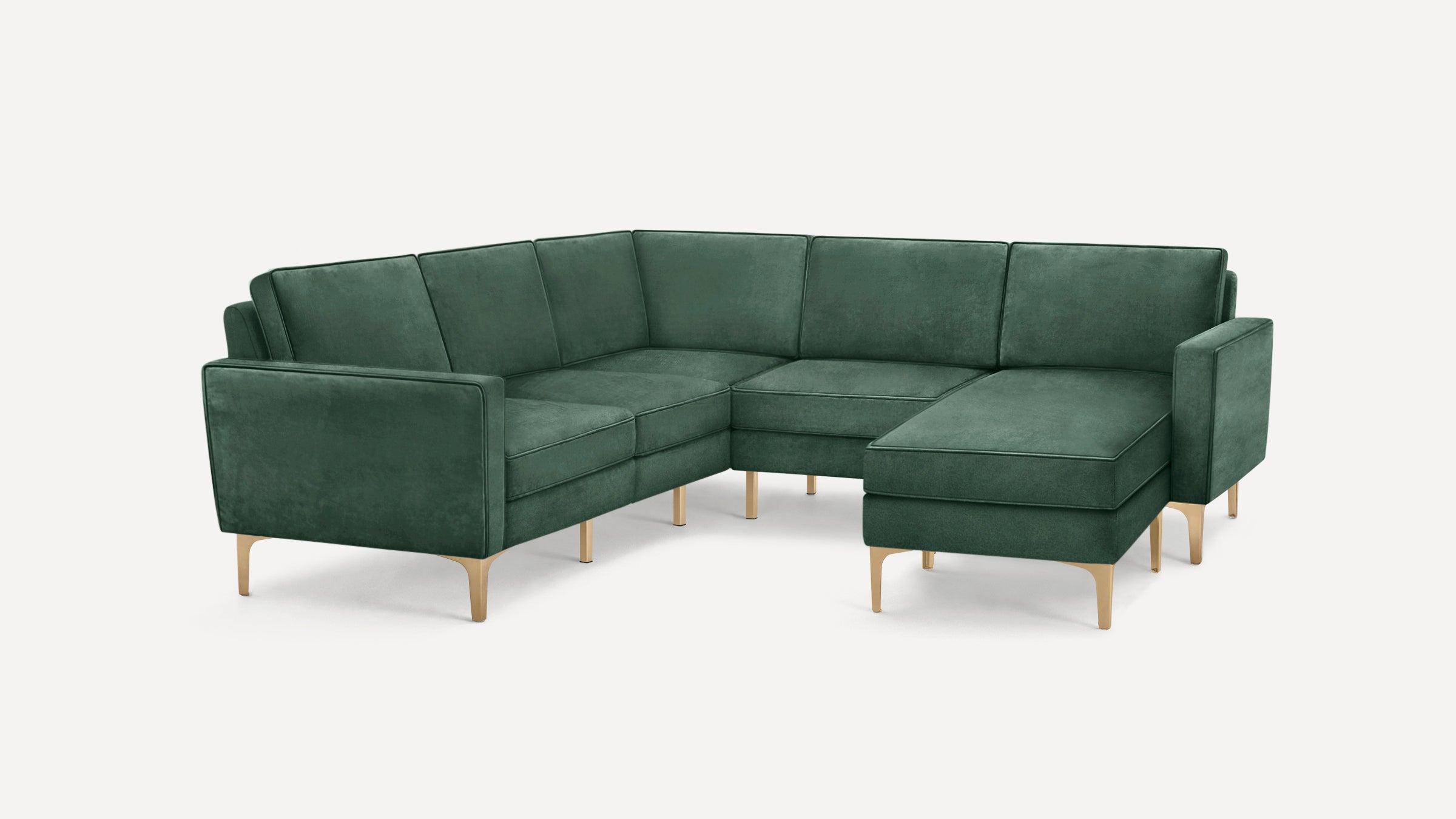Modern sectional sofa in deep green velvet upholstery with clean lines and light wooden legs on a plain background.