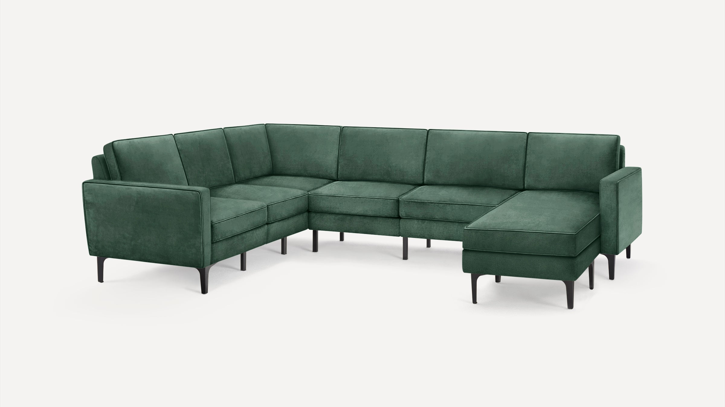 Modern dark green velvet L-shaped sectional sofa with slim black legs on a white background.