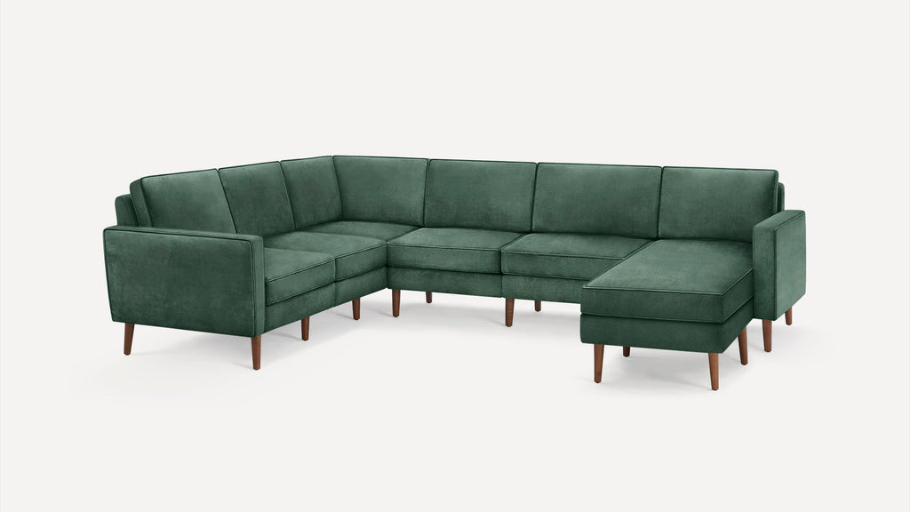 Green velvet L-shaped sectional sofa with wooden legs and modern, clean-lined design against a white background.