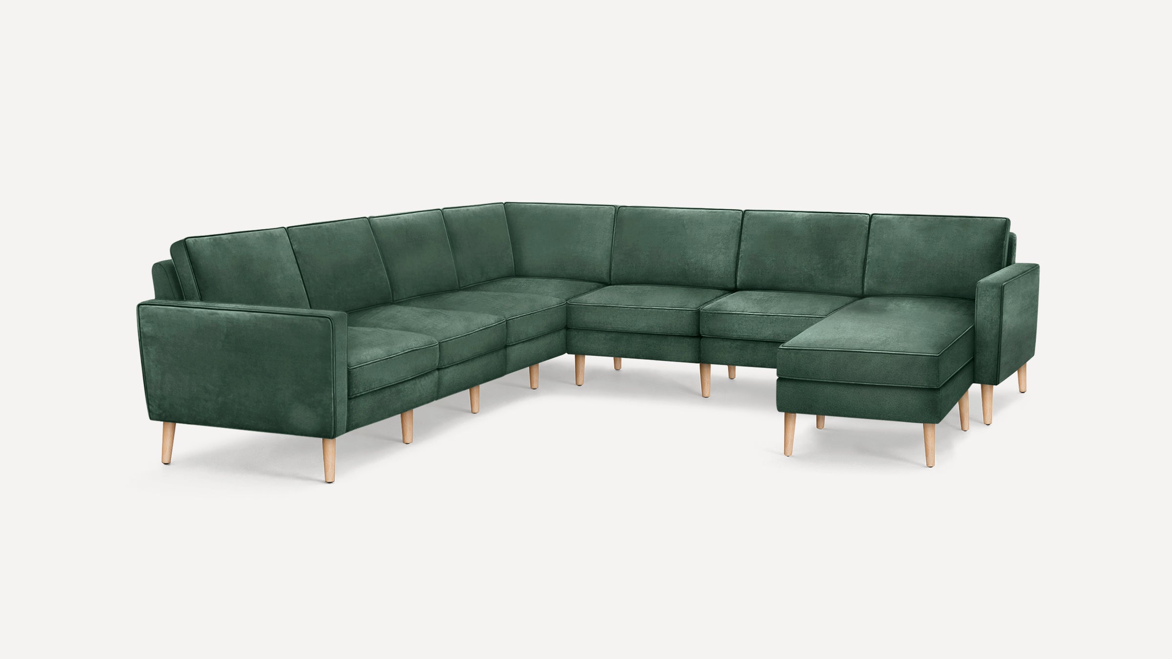 Green velvet sectional sofa with wooden legs, featuring a modern design and spacious seating including a chaise lounge.