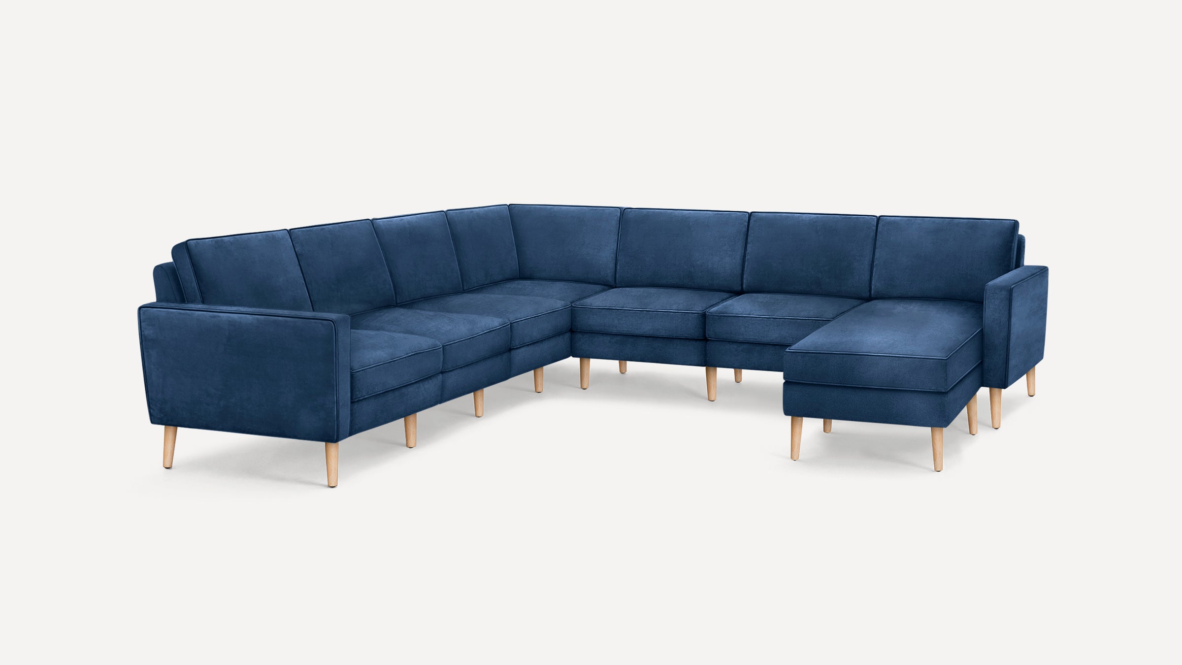 Large U-shaped sectional sofa in dark blue fabric upholstery with light wooden tapered legs and clean, modern design.