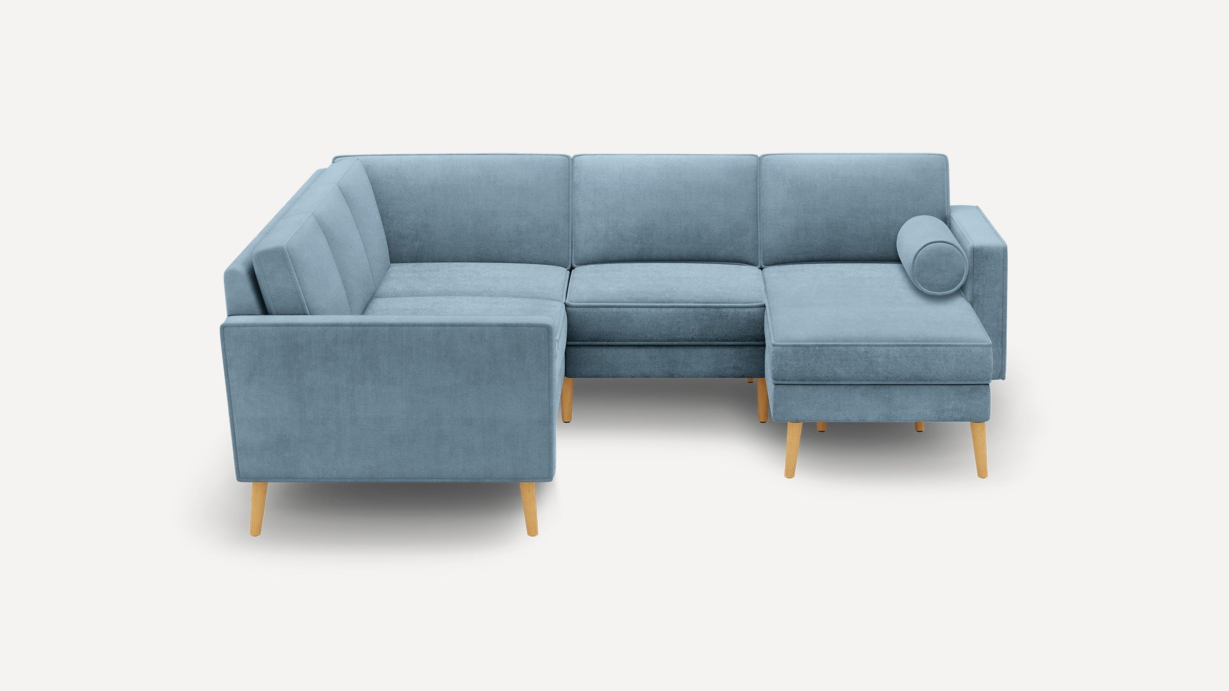 Modern light blue L-shaped sectional sofa with wooden legs and a cylindrical bolster pillow on the right side chaise lounge.