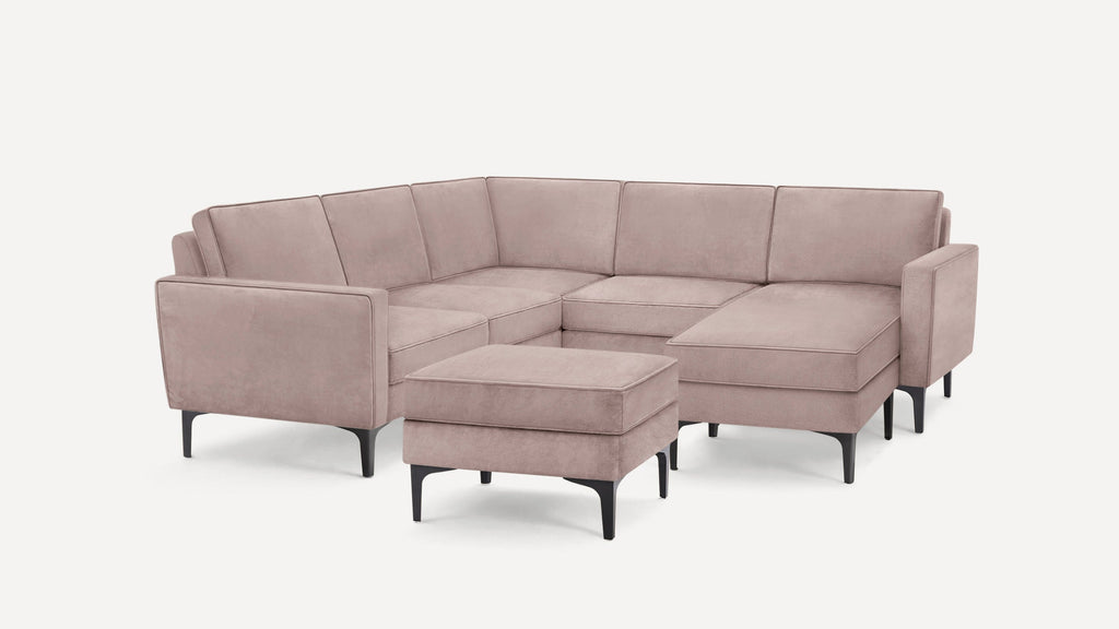 Modern light mauve velvet sectional sofa with black angled legs and matching ottoman on white background.