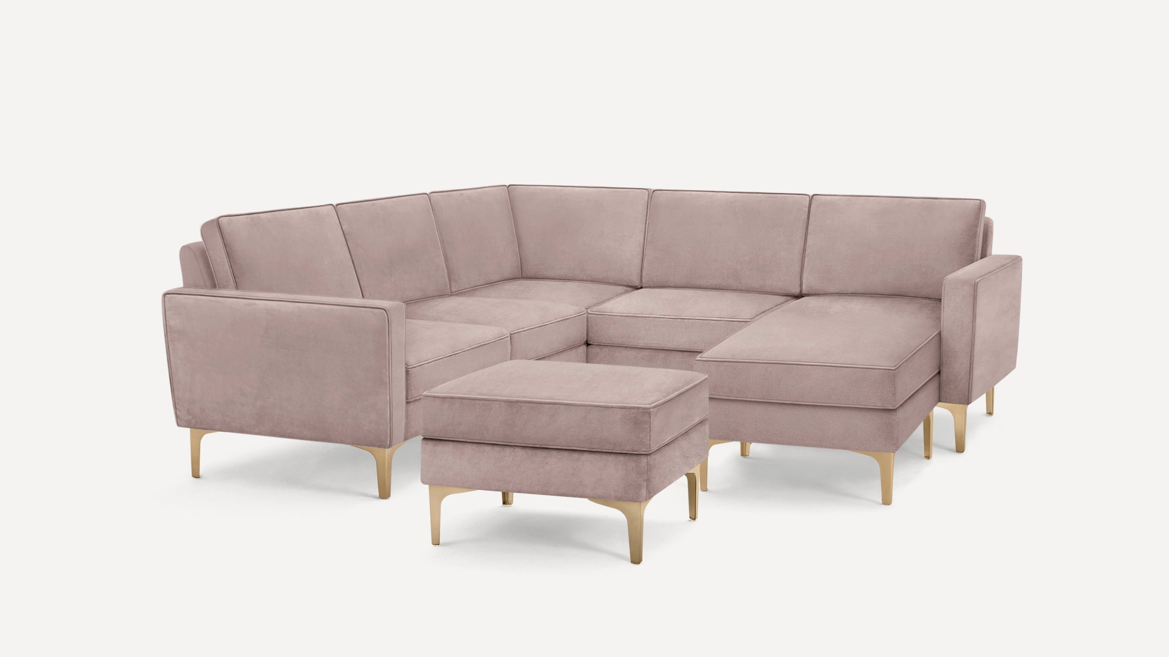 Modern L-shaped sectional sofa in dusty pink velvet with gold metal legs, including a matching ottoman.