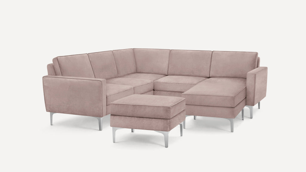 Modern L-shaped sectional sofa in muted pink fabric with clean lines and metal legs, including a matching ottoman.