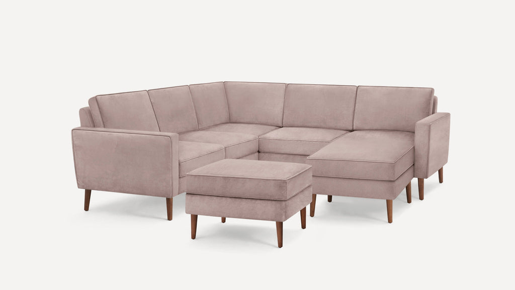 Light mauve velvet upholstered L-shaped sectional sofa with wooden tapered legs and matching ottoman.