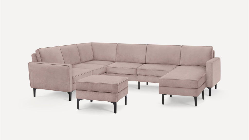 Modern blush pink fabric sectional sofa with a matching ottoman and black tapered legs on white background.